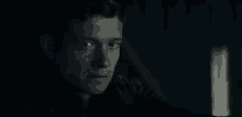 a man is sitting in a dark room looking at something .