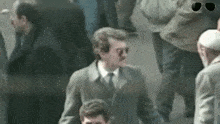a man in a suit and tie is walking in a crowd