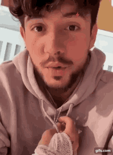 a man with a beard is wearing a hoodie and holding something in his hand .
