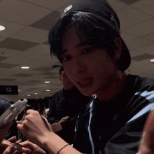 a young man with blue hair is holding a cell phone in his hand in a crowded room .
