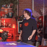 a man in a black shirt with a red heart on it is playing ping pong on a table