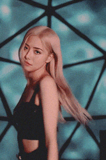 a woman with blonde hair and green eyes is standing in front of a blue background