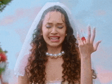 a woman in a bride 's dress is crying and holding a bloody ring on her finger .