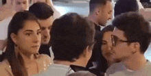 a group of people are standing in a crowd looking at each other .