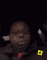 a man is sitting in the back seat of a car with a snapchat sticker on his jacket .