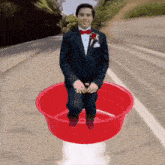 a man in a tuxedo is sitting in a red bowl of water