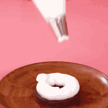a chocolate donut with whipped cream on top of it on a wooden plate