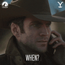 a man wearing a cowboy hat is talking on a cell phone and the word when is above him
