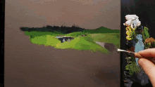 a person is painting a landscape with a palette and brush