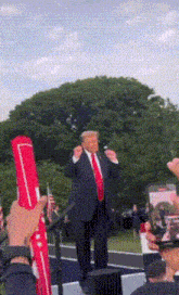 a man in a suit and tie stands in front of a crowd holding a red flag