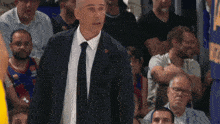 a man in a suit and tie stands in front of a crowd with the number 17 on the wall