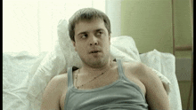 a man in a tank top is laying in a bed