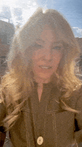 a woman with long blonde hair is standing in front of a building and smiling .