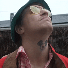 a man with a mickey mouse tattoo on his neck is wearing sunglasses