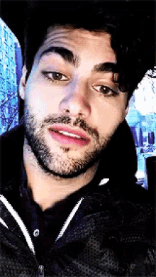 a man with a beard is wearing a black hoodie