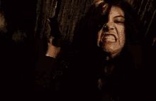 a woman is making a funny face in a dark room while another woman holds her hair .