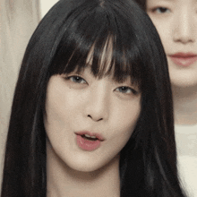 a close up of a woman 's face with long black hair and bangs
