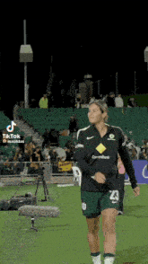 a female soccer player wearing a number 23 jersey walks on the field