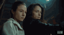 two women are standing next to each other with the letters hw on the bottom right