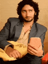 a man in a blue suit is holding a cell phone