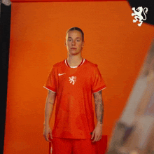 a woman wearing a red nike shirt with a lion on it poses for a picture