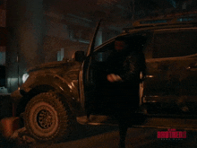 a man with a beard is standing next to a car with the word brothers written on the bottom