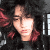 a girl with black and red hair is wearing a black hoodie .