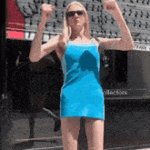 a woman in a blue dress flexes her muscles in front of a sign that says frank