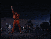 a man in red pants stands in front of a crowd of zombies