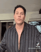 a man wearing a black striped shirt has a tiktok sticker on his shirt