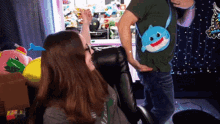 a woman sitting in a chair with a baby shark purse on her shoulder