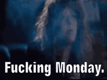 a woman is smoking a cigarette in a dark room with the words `` fucking monday '' written on the screen .