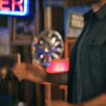 a man is holding a wheel in front of a neon sign that says ' er ' on it