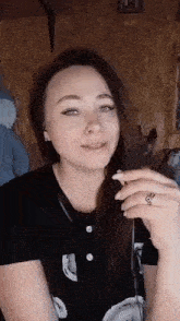 a woman is smoking a cigarette in a room while wearing headphones and a ring .