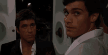 two men are standing next to each other in a dark room looking at each other .