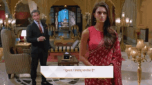 a woman in a red saree stands next to a man in a suit