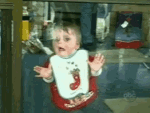 a baby wearing a bib with a christmas stocking on it looks surprised