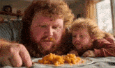 a man and a child are eating macaroni and cheese together