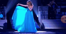 a woman in a blue dress is dancing on a stage in front of a facebook logo