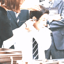 a man in a suit has his hair cut by a woman
