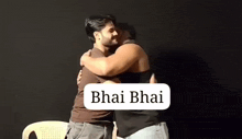 two men are hugging each other in front of a black background with the words bhai bhai written on it .