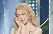 a woman with blonde hair is covering her face with her hand
