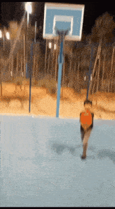 a person is playing basketball on a blue court at night