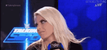a blonde woman is sitting in front of a microphone on a blue background .