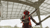 a man in a red and black costume holds two swords