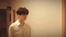 a man in a white shirt stands in a hallway