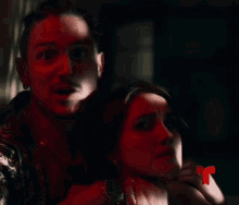 a man is holding a woman 's neck with a red t in the corner