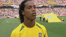 a soccer player stands on a field with a banner behind him that says adidas