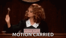 a woman in a judge 's robe is holding a hammer in her hand .