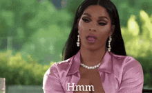 a woman in a pink shirt and earrings is sitting at a table and talking .